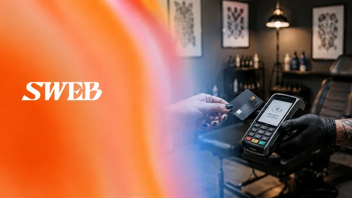 Paiement par carte sans contact sur un terminal tenu par un tatoueur ganté.